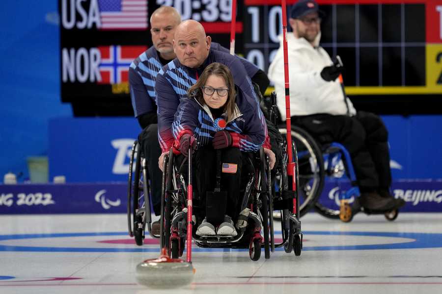 Pamela Wilson of the United States pushes a stone as teammates Steve Emt and Dave Samsa assist during their wheelchair curling match against Norway at the 2022 Winter Paralympics, Monday, March 7, 2022, in Beijing.