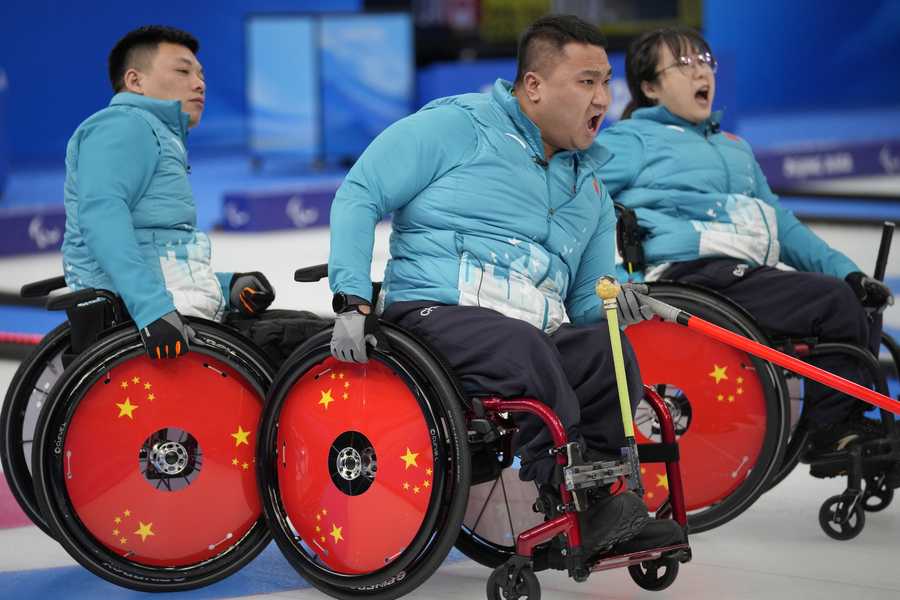China's Wang Haitao, center, Yan Zhuo, right, and Zhang Mingliang react during their wheelchair curling match against Switzerland at the 2022 Winter Paralympics, Monday, March 7, 2022, in Beijing.