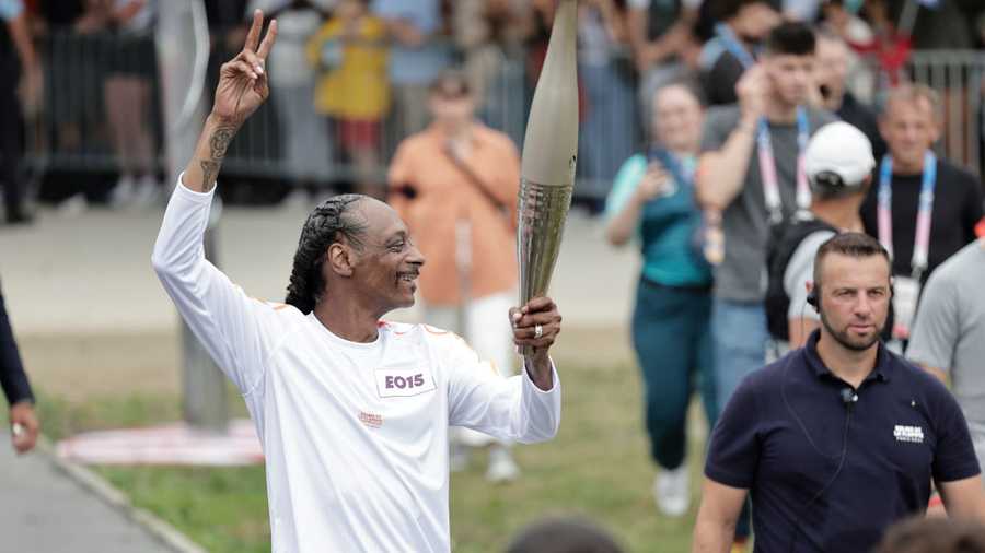 PARIS, FRANCE - JULY 26: US rapper Snoop Dogg makes a peace sign as he holds the torch as part of the 2024 Paris Olympic Games Torch Relay, in Saint-Denis on July 26, 2024 in Paris, France. (Photo by Stephane De Sakutin - Pool/Getty Images)