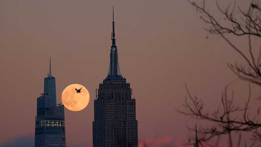 JERSEY CITY, NJ - DECEMBER 4: The full Cold Moon supermoon rises behind the Empire State Building and One Vanderbilt as the sun sets in New York City on December 4, 2025, as seen from Jersey City, New Jersey.  (Photo by Gary Hershorn/Getty Images)