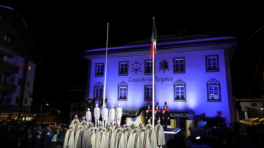 A mountain choir performs the national anthem as the flag of Italy waves during the opening ceremony of the Milano Cortina 2026 Winter Olympics at Piazza Dibona on February 06, 2026 in Cortina d'Ampezzo, Italy.