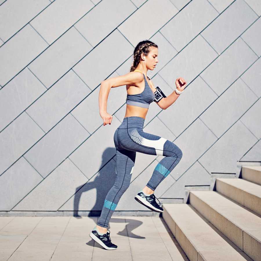 Girl is runing on the city stairs and listening the music
