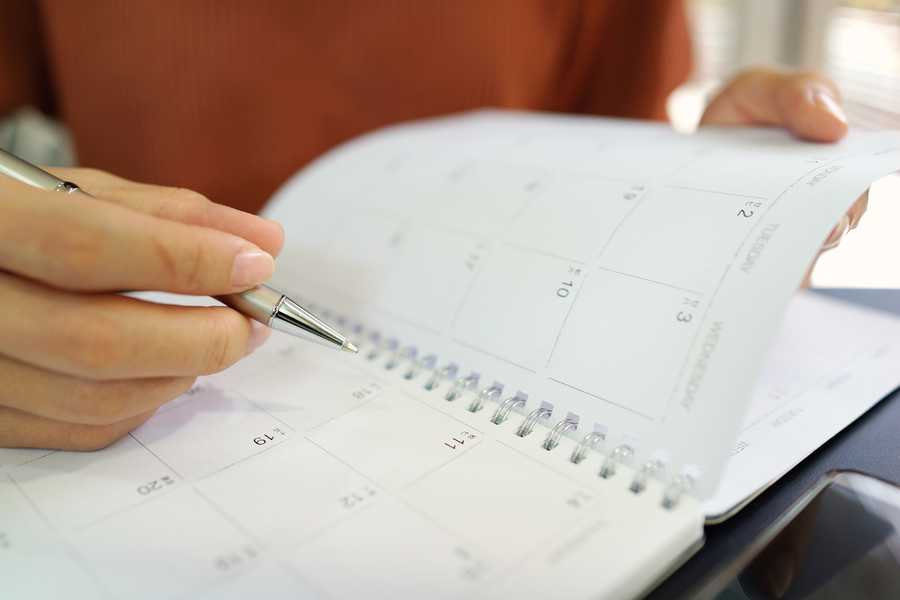 Midsection Of Woman Hand Writing With Pen In Calendar