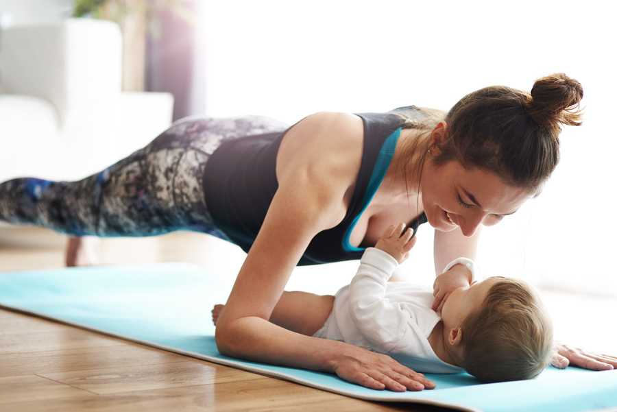 Mother with baby exercising on yoga mat at home