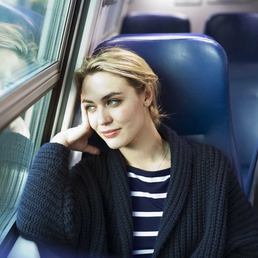 young woman on a train looking out the window